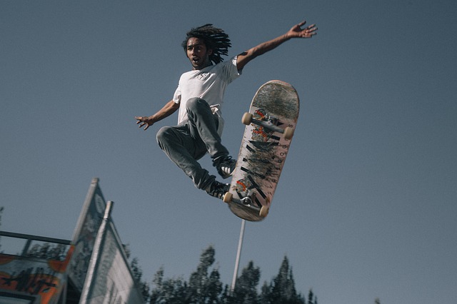 ein skater in weißem t-shirt und jeans bei einem sehr hohem sprung mit seinem skateboard