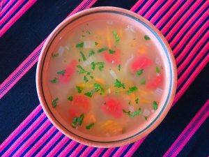 Quinoa Suppe i einer Schüssel auf einer Tischdecke in dunkel blau und knalligem rosa
