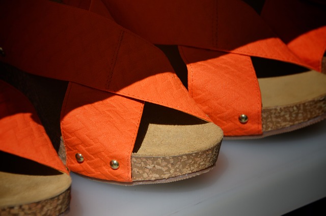 nahaufnahme eines regals in einem Schuhladen auf dem orangene offene Sandalen aufgereiht sind
