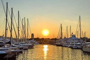 Hafen von Barcelona in der Mitte die untergehende Sonne und and den Seiten geparkte Schiffe