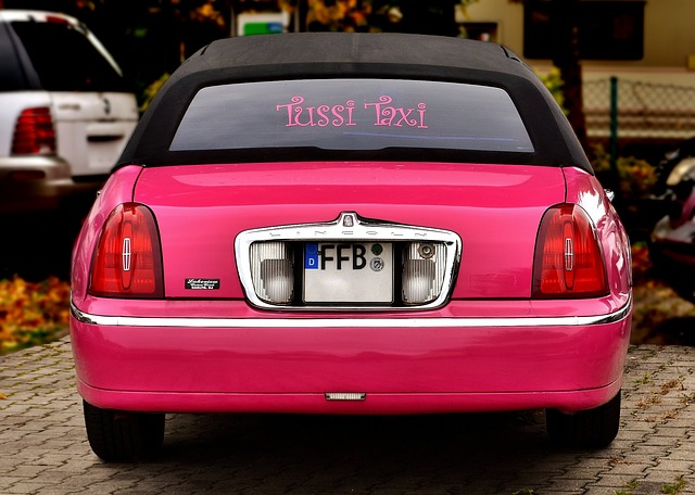 ein rosanes Cabrio auf dem auf der hinteren Heckscheibe Pussy Taxi steht