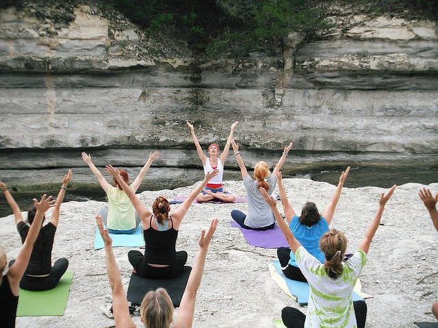 mehrere Frauen die unter freiem Himmel eine Yoga Klasse machen