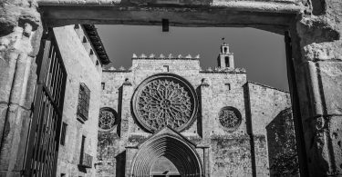 schwarz-weiss Bild der Sant Cugat Kirche, quadratische Gebäude und in der Mitte ist ein rundes verziertes Fenster