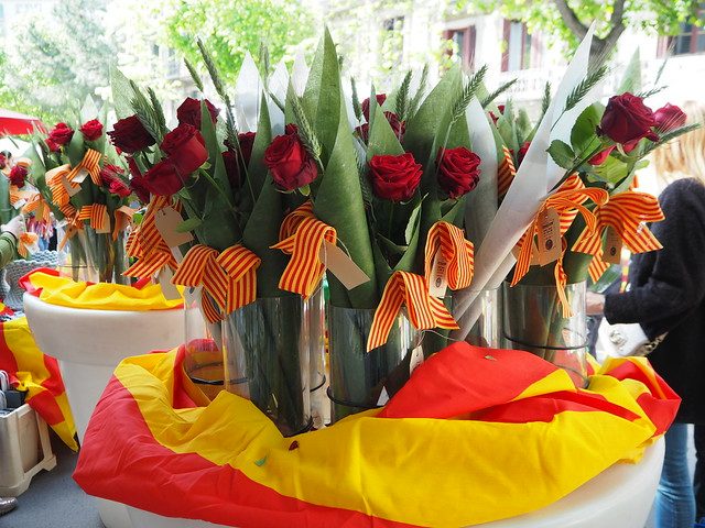 ein Tisch mit der katalanischen Flagge als Tischdecke und vielen roten Rosen darauf an einem Blumenstand zu Sant Jordi in Barcelona