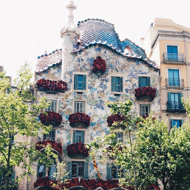 ein Gebäude des Architekten Gaudi in Barcelona, das alle Fenster und Balkone mit roten Rosen geschmückt hat