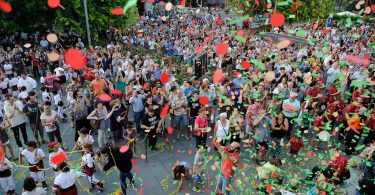 Platz mit vielen tanzenden Menschen Luftschlangen und Ballons