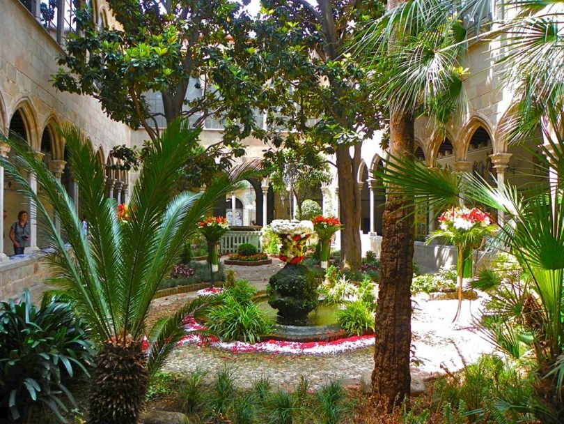 der Innenhof einer Kathedrale mit einem Blumengeschmückten kleinen Springbrunnen in der Mitte