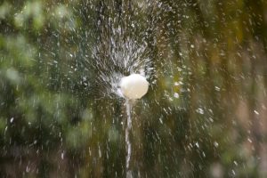 ein weißes Ei das sich auf dem Wasserstrahl eines Springbrunnens dreht