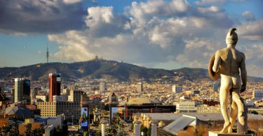 Aussicht auf Barcelona von Montjuïc aus, man sieht eine der Statuen des Nationalmuseums und ein blauer Himmel mit einigen weißen Wolken