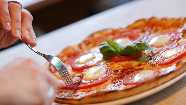 eine Person in einem Restaurant die beginnt ihre Caprese Pizza zu essen