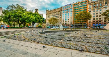 ein großer Platz in Barcelona mit Bäumen einem Springbrunnen und kreisförmig angelegte Pflastersteine