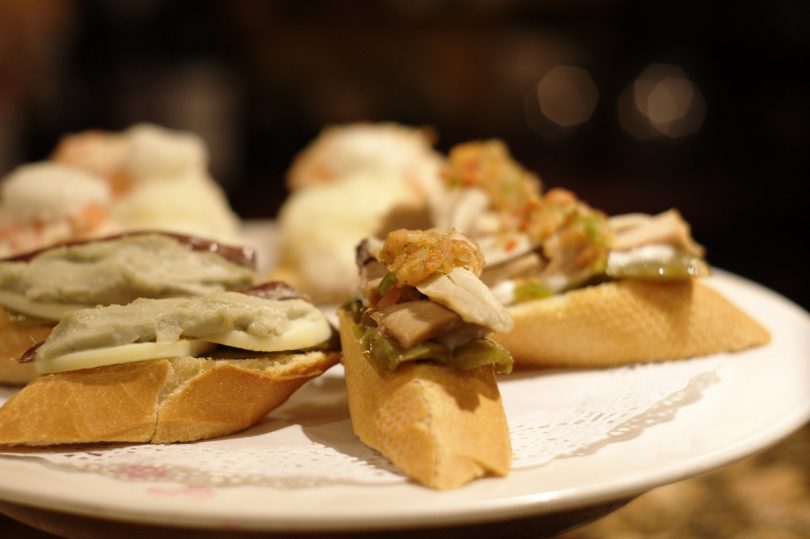 Weisser runder Teller mit Pintxos: je eine Scheibe Baquette mit grüner Paprika und Sardelle