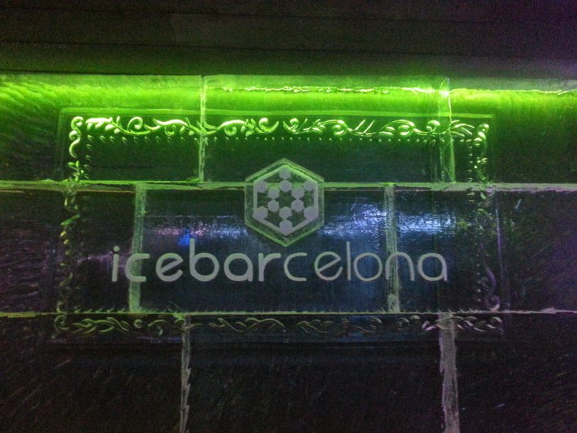 Ein Schild aus Eis, grün beleuchtet auf dem dem icebarcelona steht, bei nacht