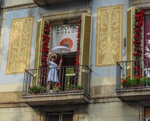 auf dem Balkon des Erotik Museums steht Marilyn Monroe in einem blauen Kleid mit einem weißen Sonnenschirm und winkt den Passanten zu