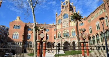 Frontaufnahme eines der Gebäude des Hospital de Sant Pau, es ist eingeweiht und hat große Treppen vor dem Haupteingang