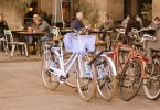 mehrere Fahrräder die vor einer Terrasse eines Café geparkt sind