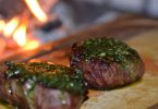 zwei saftig angebratene Steaks mit grünem chimichurri darauf