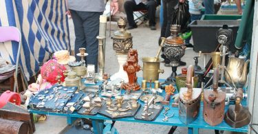 kleiner stand auf einem Flohmarkt, zum verkauf stehen kleine Antiquitäten wie Kerzenhalter und Bügeleisen