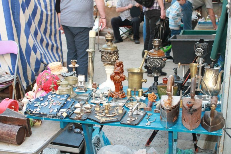 kleiner stand auf einem Flohmarkt, zum verkauf stehen kleine Antiquitäten wie Kerzenhalter und Bügeleisen