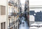 eine Nebenstraße in Barcelona mit kleinen Geschäften und einigen katalanischen Flaggen