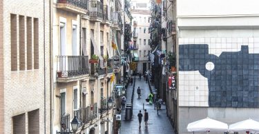 eine Nebenstraße in Barcelona mit kleinen Geschäften und einigen katalanischen Flaggen