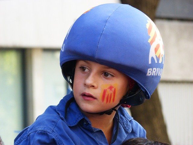 Kind einer Catellers Gruppe mit blauem Helm und Poloshirt und auf der Wange hat es die katalanische Flagge gemalt