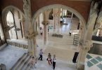 eine der Innenhallen des Krankenhauses, mit gewölbten Decken, Boden und Säulen aus weissem Mamor und vereinzelten Besuchern