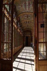 einer der Gänge des Gebäudes, verglaste Holztüren, große Fenster und bemalte Decken