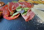 schwarzes Schieferbrett mit Wurst und Käse darauf