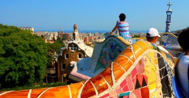 Leute auf den bunten Bänken die die Aussicht auf Barcelona geniessen