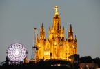 die große Kirche auf dem Tibidabo Berg beleuchtet bei Nacht und links daneben das Riesenrad des Vergnügungsparks