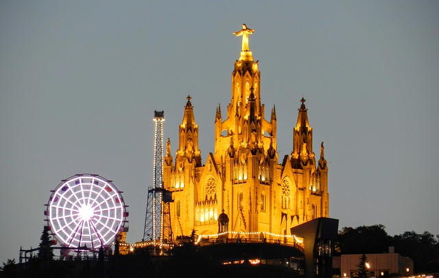 die große Kirche auf dem Tibidabo Berg beleuchtet bei Nacht und links daneben das Riesenrad des Vergnügungsparks