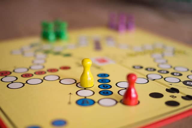 ein Mensch ärgere dich nicht Brettspiel mit verschiedenfarbigen Spielfiguren - gelb, rot, grün, lila- die auf dem dem Brett verteilt sind