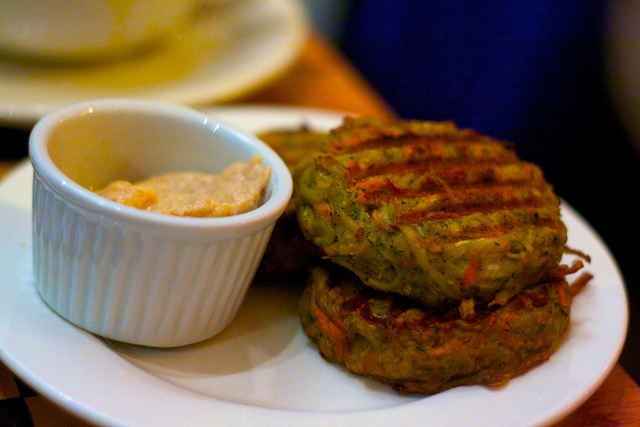 drei Hamburger, der dritte liegt auf den anderen zweien und daneben ein kleines weisses Schüsselchen mit einer orangenen Sauce