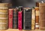 kleiner Ausschnitt eines Bücherregals mit verschiedenen alten und gebrauchten Bücher in braun, rot, schwarz und beige