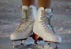 weiße Schnürschlittschuhe auf dem Eis die von einer Person getragen werden