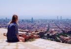 eine Frau die auf einer Treppe sitzt und die Aussichten auf die Stadt genießt