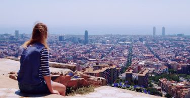 eine Frau die auf einer Treppe sitzt und die Aussichten auf die Stadt genießt