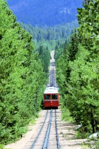 ein gang durch den dichten Wald wo die rote Bahn auf schienen auf den Berg fährt