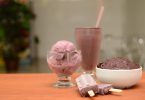 auf einem Tisch liegen zwei schokoeis am Stil, ein glas mit schokoeis ein hoher Becher und ein tiefer Teller ebenfalls mit schokoeis