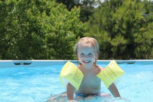 Kleines Kind lächelt fröhlich während es im Pool spielt