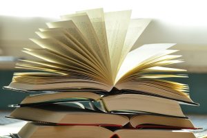 gestappelte offene Bücher wobei das oberste einen Fecher mit den Seiten bildet