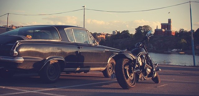 Parkplatz an einer Meeresbucht auf dem ein schwarzes Auto und ein schwarzes Motorrad stehen