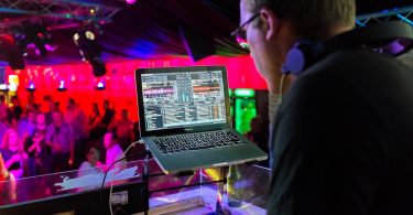 Dj in einer Disco der Musik mit Hilfe eines Laptops auflegt