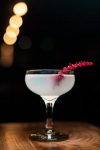 Cocktail in klassisches champangerglass mit langer roter Stilblüte drin