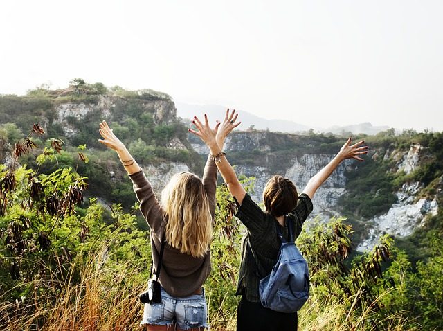 Zwei Frauen mitten in der Natur die vor Freude die Arme in die Luft reisen