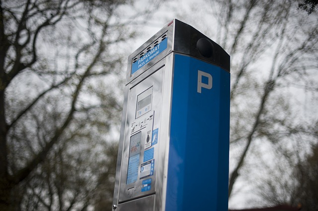 eine blaue moderne Parkuhr mit Bäumen im Hintergrund