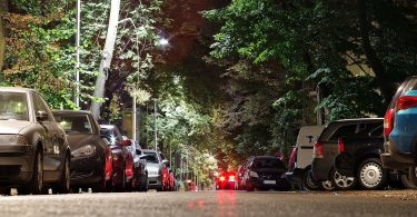 Eine breite Allee mit geparkten Autos auf beiden Seiten