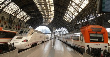 Hauptbahnhof in Barcelona mit zwei Renfe Zügen, einer weiss grau und einer weiss orange