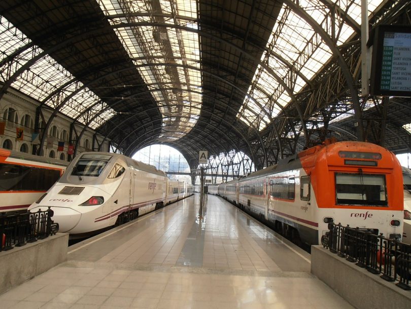 Hauptbahnhof in Barcelona mit zwei Renfe Zügen, einer weiss grau und einer weiss orange